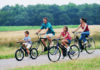 Person riding a bicycle on a bright summer morning, representing best cycles for hot-weather riding in 2026