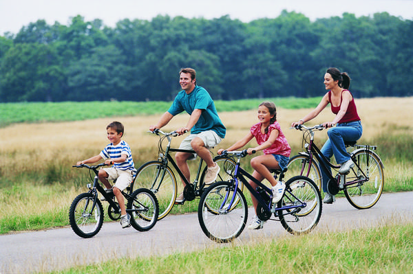 Person riding a bicycle on a bright summer morning, representing best cycles for hot-weather riding in 2026
